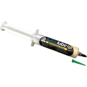 A syringe-like applicator of DayLube Nanoceramic Grease with a black and yellow label, accompanied by a loose green nozzle cap nearby.